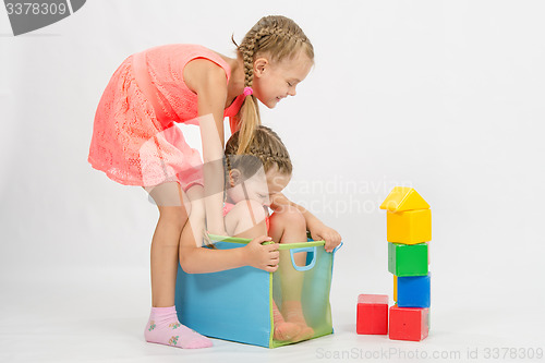 Image of Girl tries to pull another girl out of the box