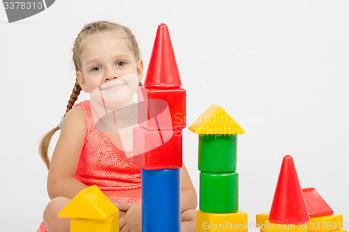Image of The four-year girl sits at a house out of blocks