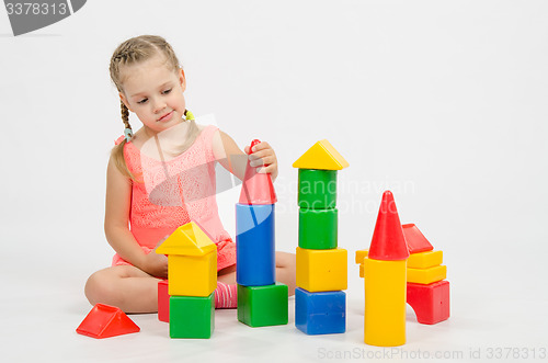 Image of The girl puts on a tower house from cubes