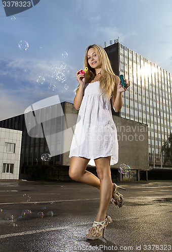 Image of woman blowing soap bubbles on street 