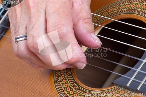 Image of Old woman\'s hand playing guitar