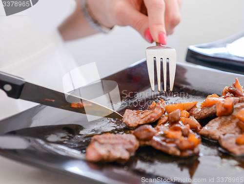 Image of dish of pork with sauce on black plate