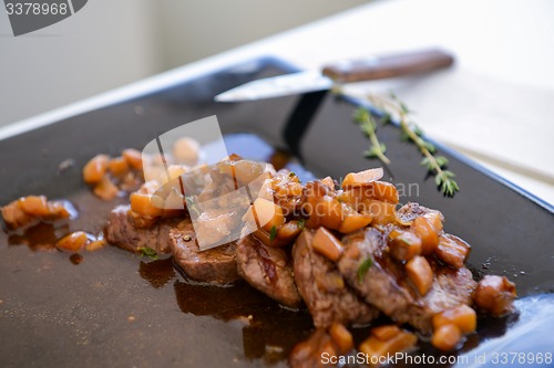 Image of dish of pork with sauce on black plate