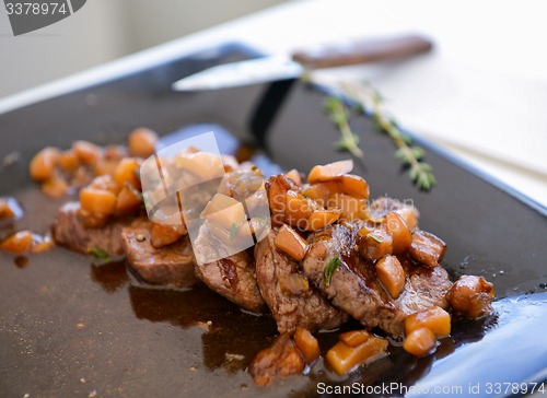 Image of dish of pork with sauce on black plate
