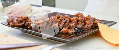 Image of dish of pork with sauce on black plate