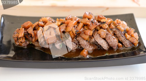 Image of dish of pork with sauce on black plate