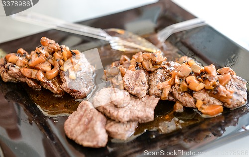 Image of dish of pork with sauce on black plate