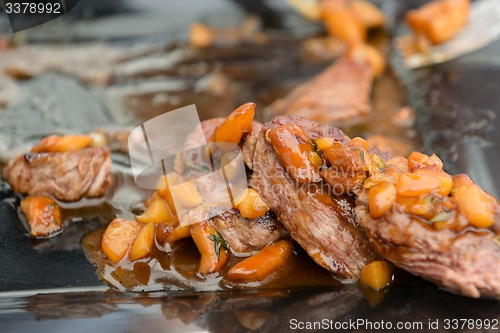 Image of dish of pork with sauce on black plate