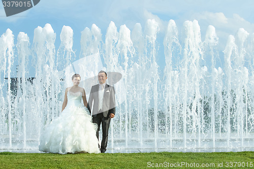 Image of Bride and groom in front of water spray fountain