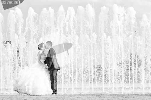 Image of Bride and groom kissing in front of water fountain black and whi