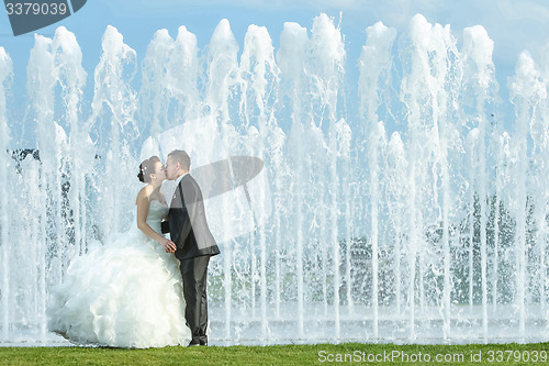 Image of Bride and groom kissing in front of water fountain