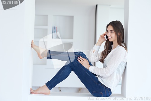 Image of young woman using cellphone at home