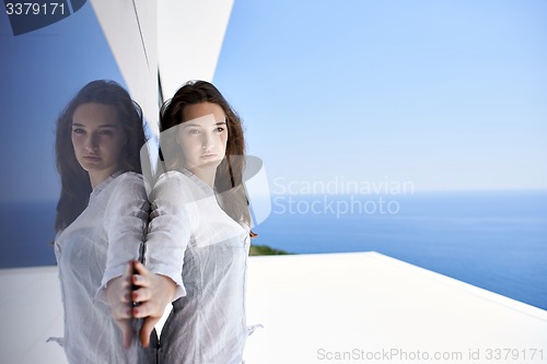 Image of relaxed woman in front of luxury modern home