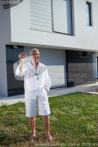 Image of senior man in front of modern home