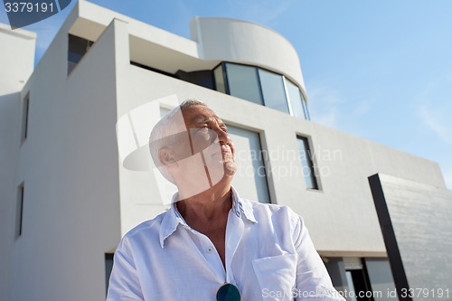 Image of senior man in front of modern home