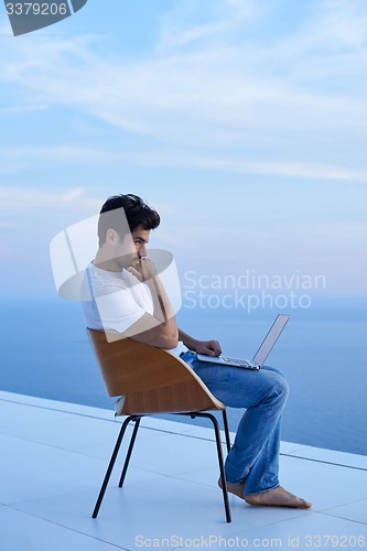 Image of relaxed young man at home on balcony