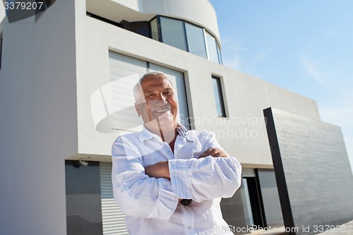 Image of senior man in front of modern home