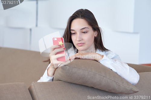 Image of young woman using cellphone at home