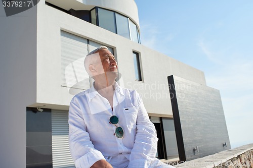 Image of senior man in front of modern home