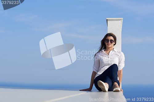 Image of relaxed woman in front of luxury modern home