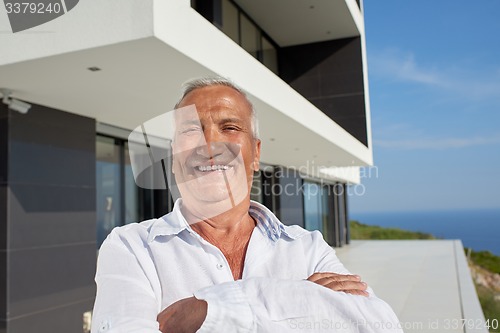 Image of senior man in front of modern home