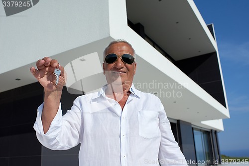 Image of senior man in front of modern home