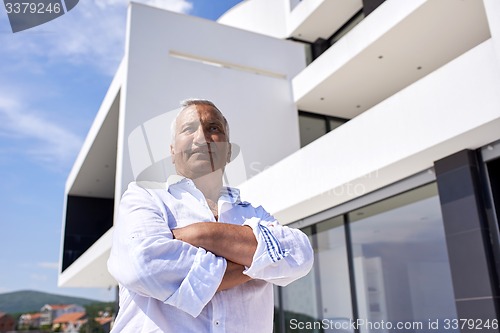 Image of senior man in front of modern home