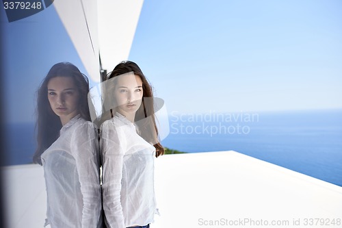 Image of relaxed woman in front of luxury modern home