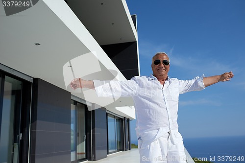 Image of senior man in front of modern home