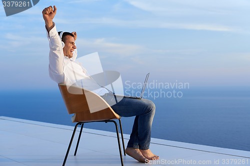 Image of relaxed young man at home on balcony