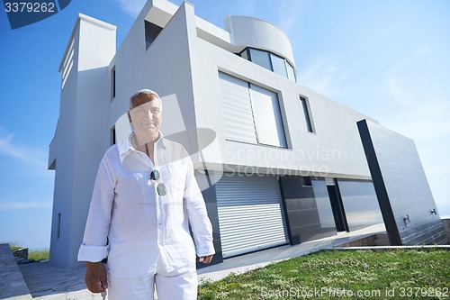 Image of senior man in front of modern home