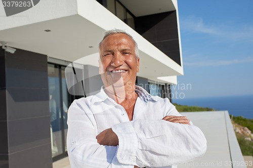 Image of senior man in front of modern home