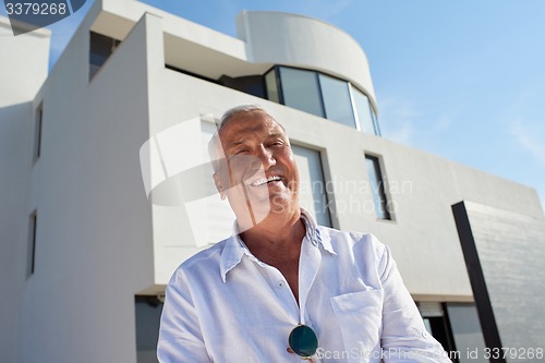 Image of senior man in front of modern home