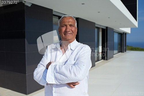 Image of senior man in front of modern home