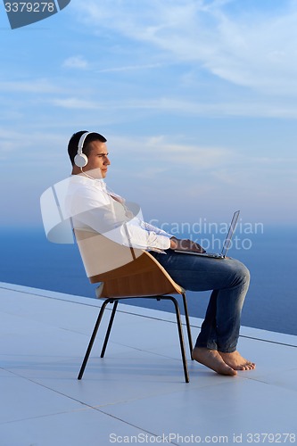 Image of relaxed young man at home on balcony