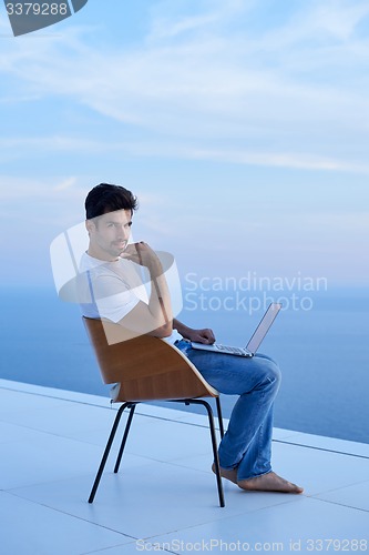 Image of relaxed young man at home on balcony