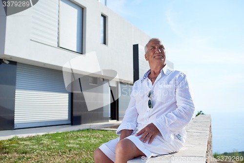 Image of senior man in front of modern home