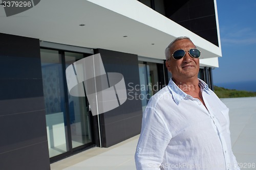 Image of senior man in front of modern home