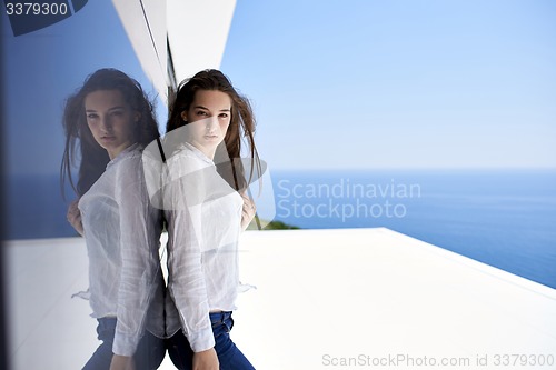 Image of relaxed woman in front of luxury modern home