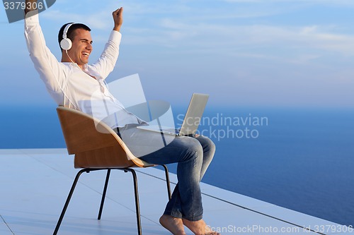 Image of relaxed young man at home on balcony