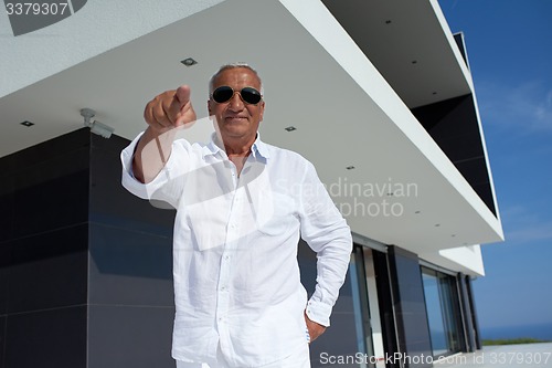 Image of senior man in front of modern home