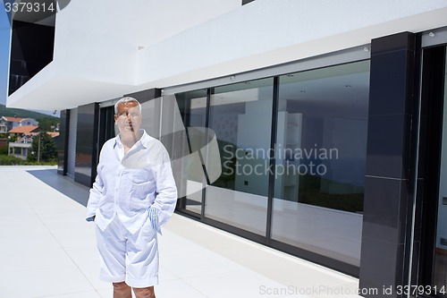 Image of senior man in front of modern home