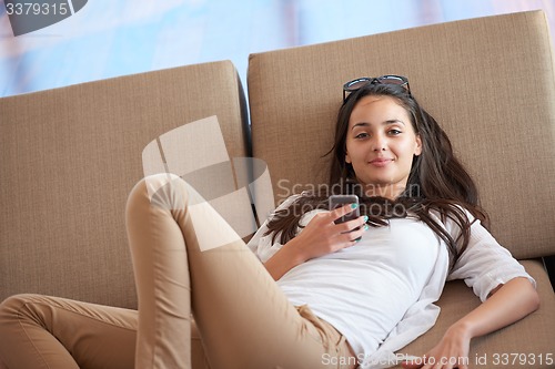 Image of young woman using cellphone at home