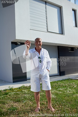 Image of senior man in front of modern home