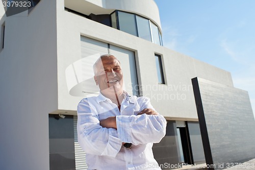 Image of senior man in front of modern home