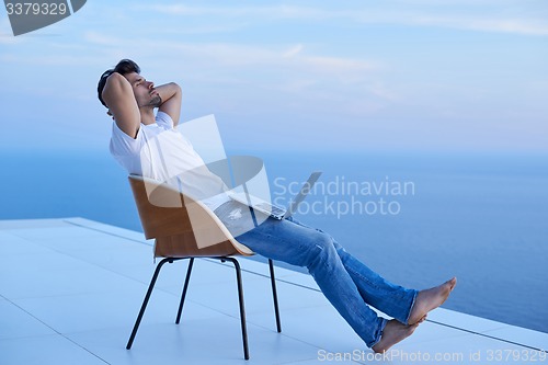 Image of relaxed young man at home on balcony