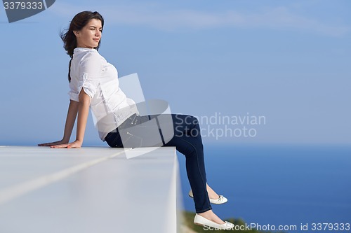 Image of relaxed woman in front of luxury modern home