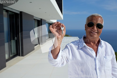 Image of senior man in front of modern home