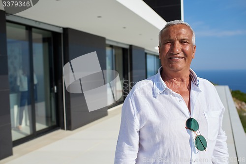 Image of senior man in front of modern home