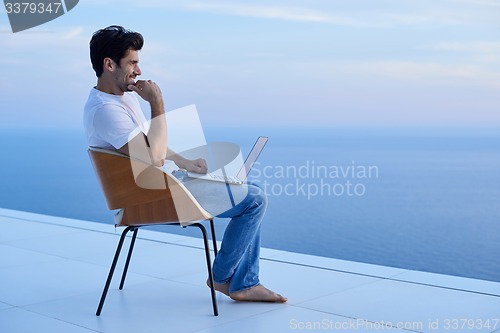 Image of relaxed young man at home on balcony